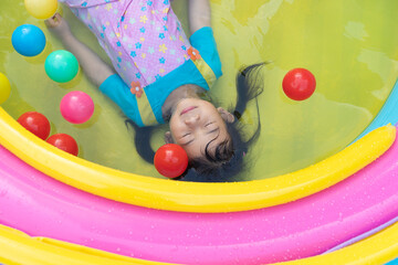 Obraz premium Asian cute girl playing in inflatable baby pool.