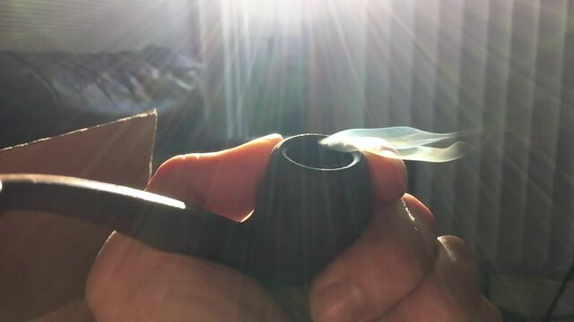 Close up shot of a smoldering pipe load of whatever your imagination desires for this type of thing. Really it's a fat bowl of amazing chronic weed from California USA in the height of a Pandemic