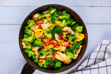 Vegetable dish stir fry with chicken in pan on white surface.
