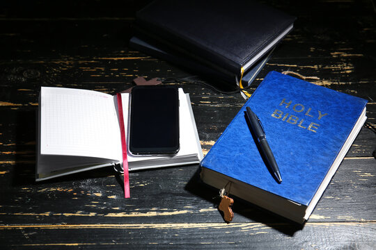 Holy Bible, notebook and mobile phone on table