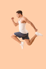 Sporty jumping young man on color background