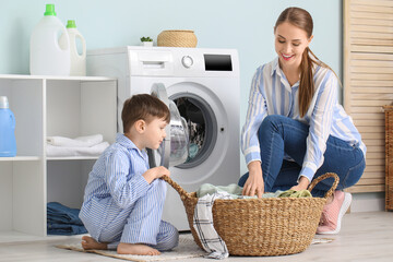 Young woman with her little son doing laundry at home
