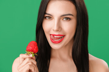 Sexy young woman with strawberry on color background