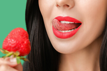 Sexy young woman with strawberry on color background, closeup