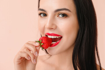 Sexy young woman with strawberry on light background