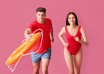 Running beach rescuers with lifebuoy on color background