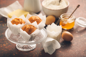 Stand with tasty muffins and cups on color background