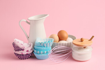 Muffin baking cups with products on color background