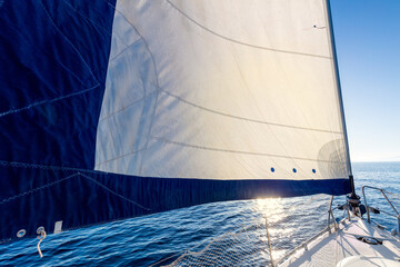 Sail boat yacht with set up sails gliding in open sea at sunrise