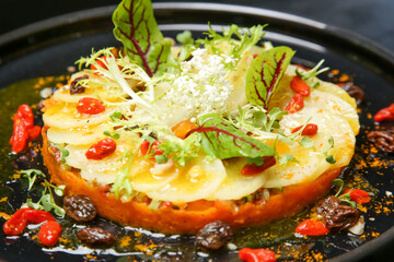 Exquisite dish. Beautifly decorated healthy organic food. Modern creative restaurant meal. Wite radish and carrot pulp decorated with salad leaves and goji berries.