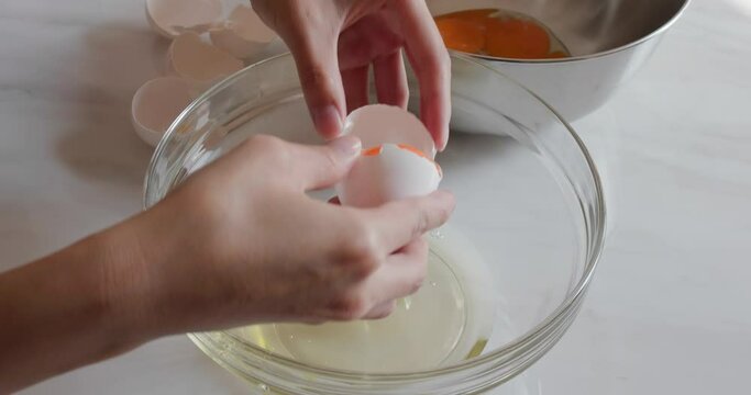 Female hands breaking an egg and separating yolk from white