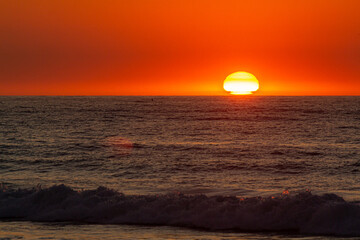 amanhecer com sol no horizonte tocando o mar e o céu todo vermelho