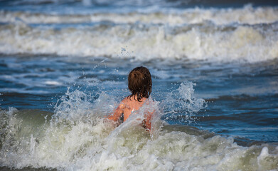 Fototapeta premium Child boy in nature with beautiful sea, sand and blue sky. Happy child playing in the sea.