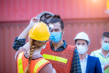 The worker used a medical Digital  temperature Thermometer to check staff body temperature before start work in factory ,they wearing face mask the concept of a corona virus [Covid-19] screening.