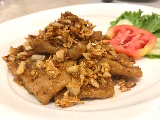 Fried pork with garlic serve with slice tomato and lettuce.