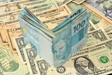 Fototapeta na wymiar Notas de 100 reais junto com dólares americanos de diversos valores