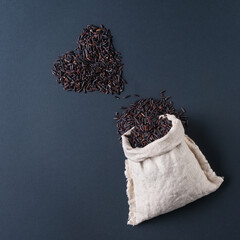 Black wild rice heart shaped and in pouch on dark background.