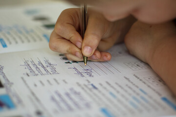 Close up of young boy doing his homework, hand with pen