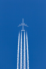 Large four engined commercial airliner jet aircraft flying at high altitude with a large contrail...