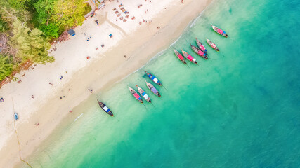 Aerial top view of crystal clear sea water and white beach with longtail boats from above, tropical island or Krabi province in Thailand
