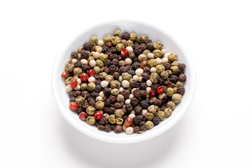 Bowl of peppercorns of various colors in a small round bowl isolated on a white background. 