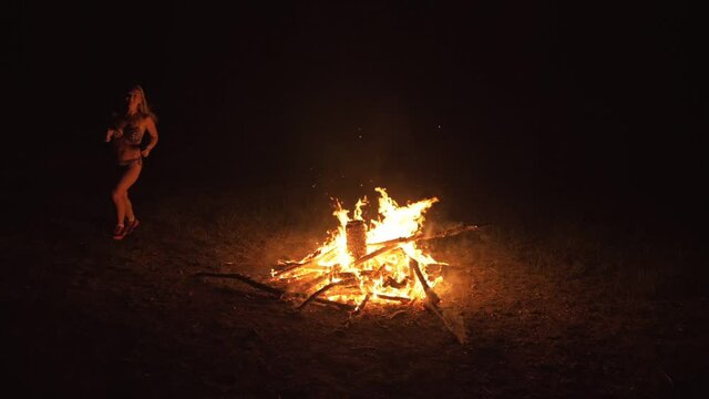 Silhouette of mystic woman in black background of fire fly flame, spark, of contour outline. Adult sexy of young girl witchcraft ceremony ritual dance in underclothes. Outdoor slow motion. Caucasian.