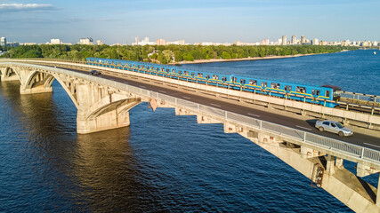 Fototapeta na wymiar Aerial drone view of Metro railway bridge with train and Dnieper river from above, skyline of city of Kyiv, Kiev cityscape, Ukraine 