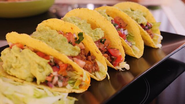 Fresh homemade hard shell tacos on a plate with delicious filling a guacamole topping - camera slide over