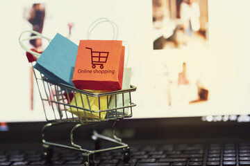 Paper shopping bags with trolley logo on laptop keyboard. Concept online shopping, e-commerce depicts customers order things from retailer sites via the internet.