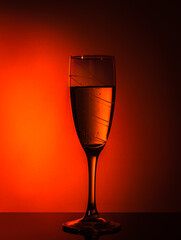 A glass of champagne on an orange background with a beautiful vignette around the edge. Idea for decorating a party or holiday