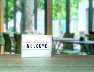 Welcome text on light box on wooden table with the blurry restaurant view background