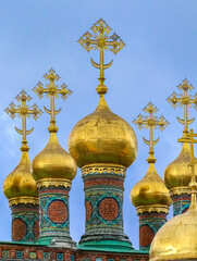 Fototapeta na wymiar Golden onion domes and crosses atop the Kremlin's Church of the Nativity, constructed in 1393 in Moscow, Russia
