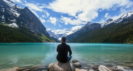 Young man looking at beautiful Lake Louise in Banff, Alberta, Canada on a blue sunny day