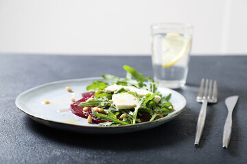 Plate with arugula, beet and feta salad. Sprinkled with pine nuts and honey