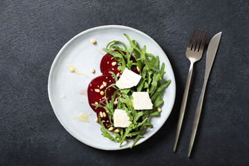Plate with arugula, beet and feta salad. Sprinkled with pine nuts and honey