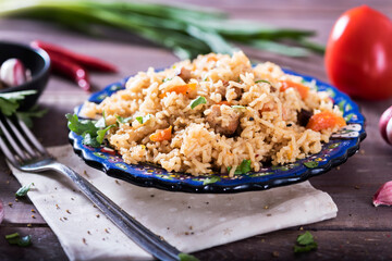 Pilaf - traditional Eastern dish made with rice, vegetables and meat. Asian food. The concept of oriental cuisine , on a wooden table