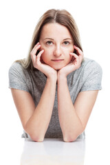 A young girl sits propping her face with her hands. Isolated on a white background. Vertical....