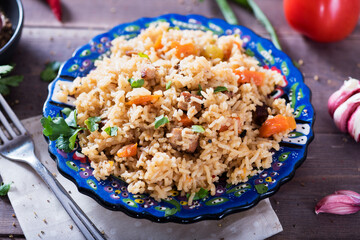 Pilaf - traditional Eastern dish made with rice, vegetables and meat. Asian food. The concept of oriental cuisine , on a wooden table