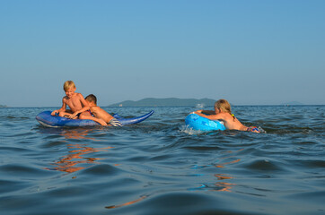 Happy group of caucasian children swim in the sea on inflatable circles on summer holidays lifestyle. Active leisure for health and sports outdoor.