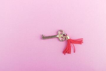 Gold metal key on light pink base, top view