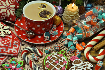 Jar with candy, cup of tea and gingerbread cookie on festive table.