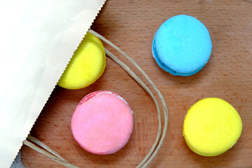 Colorful french Sweet Cakes Macaroons from paper bag onto a wooden plate.
