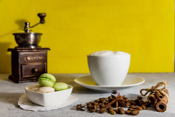 French macaroni cookies in a white heart-shaped saucer, a Cup of coffee with milk sprinkled with coffee beans. 