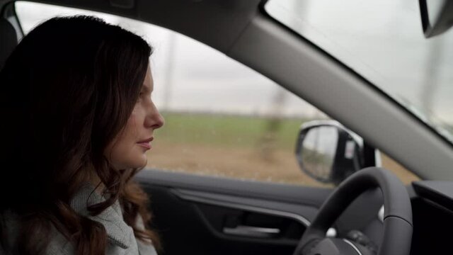 Brunette woman driver behind the steering wheel driving her crossover suv car