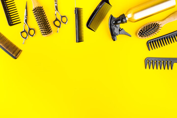 Hairdresser set in beauty salon. Combs, scissors, spray on yellow desk top-down copy space