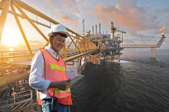 Offshore oil rig and Asian worker staff engineer hold tablet
