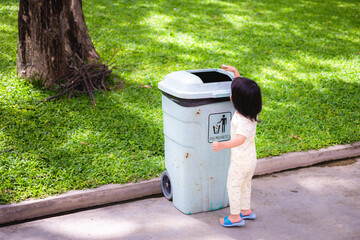 Asian baby little girl throwing garbage into trash can. Baby age 2 - 3 years old.