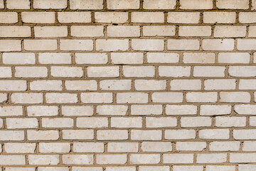 Pattern of an old exterior wall surface made of white bricks. Bricks are aged and weathered with crumbled mortar