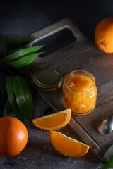 orange jam on a dark background .glass jar of orange jam with fresh fruit