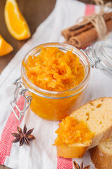 Jar of orange jam on a white napkin with slices of French baguette